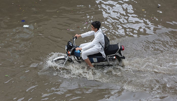 A person rides a motorbike through a flooded street after a downpour in Lahore, July 9, 2025. — Reuters
