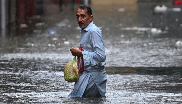 A man wades through a flooded street during heavy monsoon rains in Rawalpindi on July 17, 2025. — AFP