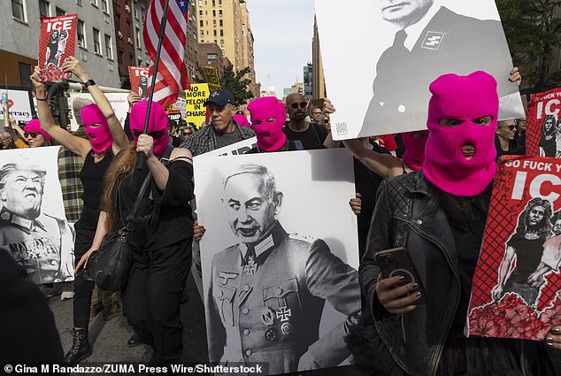 Members of the feminist art movement Pussy Riot wear hot pink balaclavas and hold signs with images of Israeli Prime Minister Benjamin Netanyahu and Donald Trump in Nazi uniforms at the No Kings march in NYC on Saturday