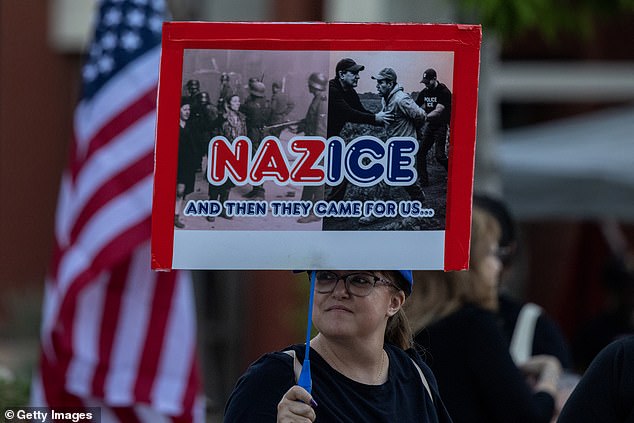 An older white woman holds a sign comparing ICE to Nazis