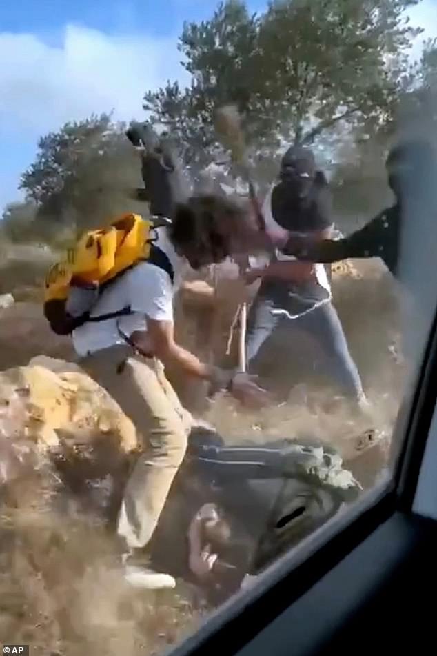 This October 19 still image taken from video shows what appear to be masked settlers beating activists and Palestinian farmers in Turmus Ayya, West Bank