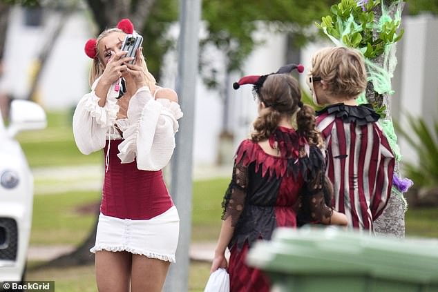 She put on a leggy display in a pair of red sling back heels as she took her children around the neighbourhood for Halloween dressed as the iconic clown from Stephen King's It
