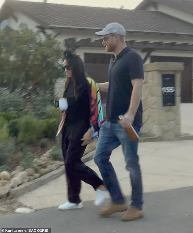 Harry appeared to be holding a water bottle in his left hand with another sticking out of his back pocket while Meghan carried a Thermos cup