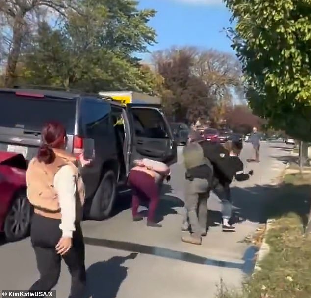 The officer pushed the woman away from a person who had their hands behind their back as other agents dealt with protestors on the other side of the vehicle