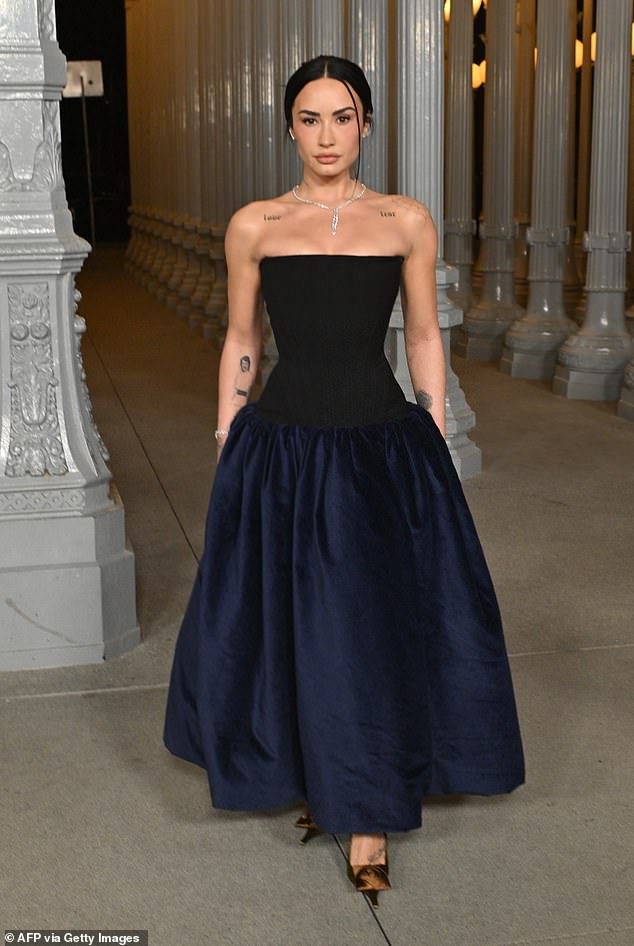 A slim-looking Demi Lovato departed from the celebratory outfits with a more formal midnight-blue off-the-shoulder gown
