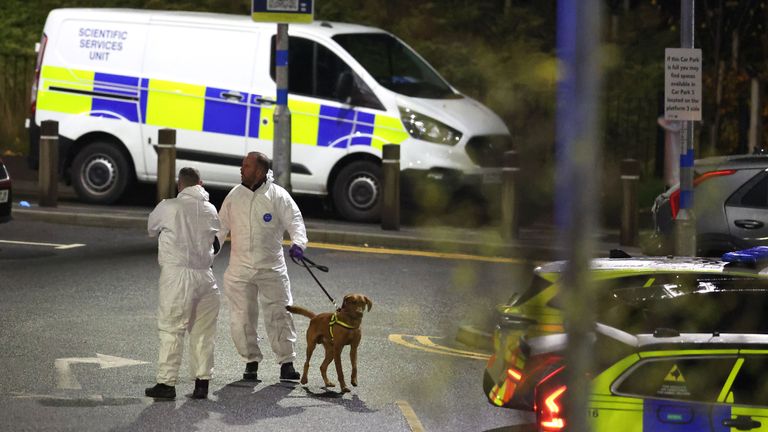 Officers wearing forensic suits with a police dog outside the station. Pic: PA