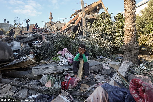 A boy reacts sitting amid the rubble of a house destroyed in an Israeli strike in Nuseira