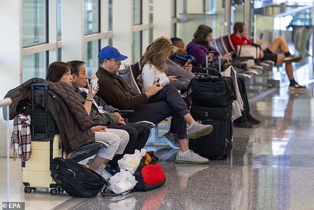 Travelers wait for their flights amid nationwide cancellations and delays at Ronald Reagan Washington National Airport in Arlington, Virginia on Friday
