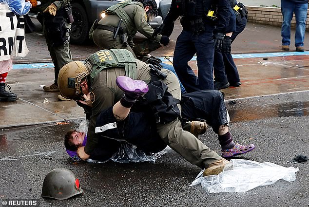 A federal officer detains a protester during a World Naked Bike Ride protest against increased activity by ICE in Portland, Oregon on October 12, 2025