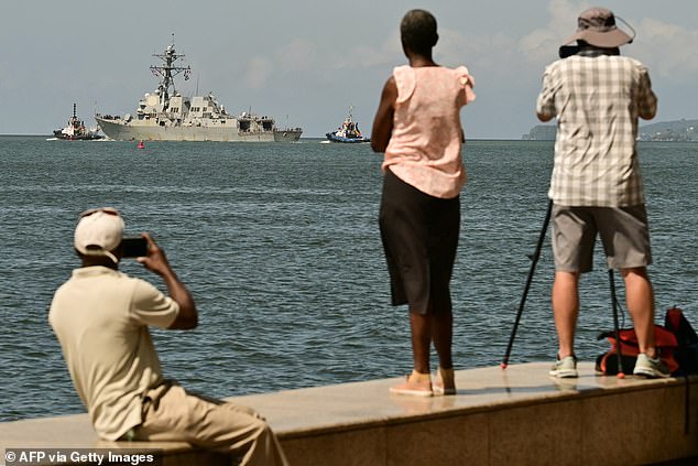 People watch and take pictures of the USS Gravely, a US Navy warship, departing the Port of Spain in Trinidad and Tobago on Thursday
