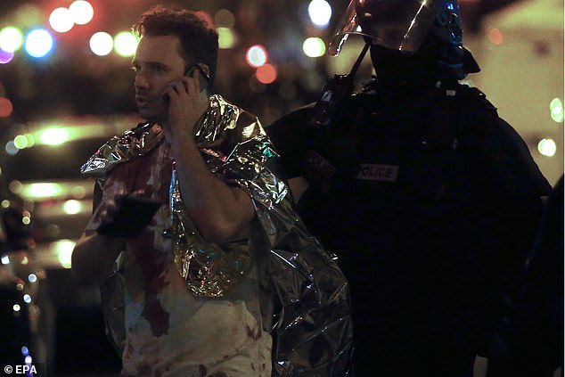 A man with blood on his shirt talks on the phone next to the Bataclan Theatre in Paris, France, on the morning of November 14, 2015