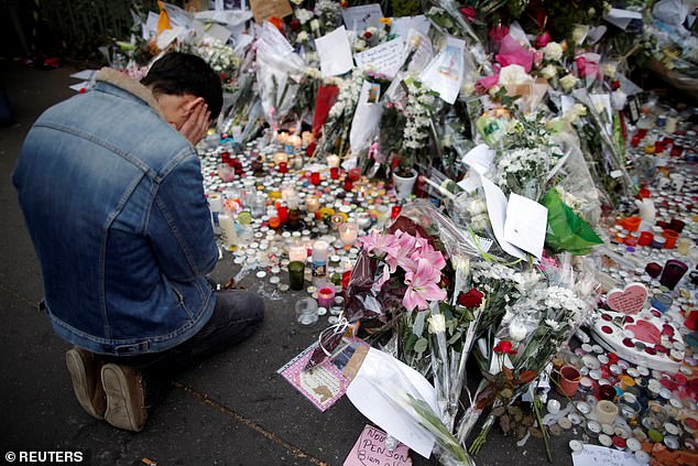 A man kneels as he pays tribute to victims near the site of the attack at the Bataclan concert hall in Paris, November 16, 2015