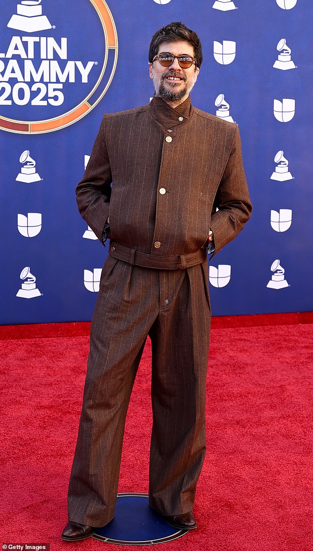 A bit too casual! Artist Tó Brandileone kept things cool and casual in a pair of dark brown, pinstriped wool trousers. He paired it with a matchinh bomber jacket that featured a high neckline, and a pair of brown sunglasses.