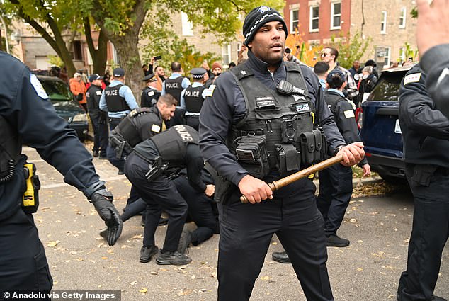 Police officers hold  batons as Immigration and Customs Enforcement (ICE) agents conduct operations in the Little Village neighborhood, a predominantly Mexican-American community