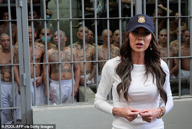 US Secretary of Homeland Security Kristi Noem speaks during a tour of the Terrorist Confinement Center (CECOT) as prisoners stand, looking out from a cell in El Salvador