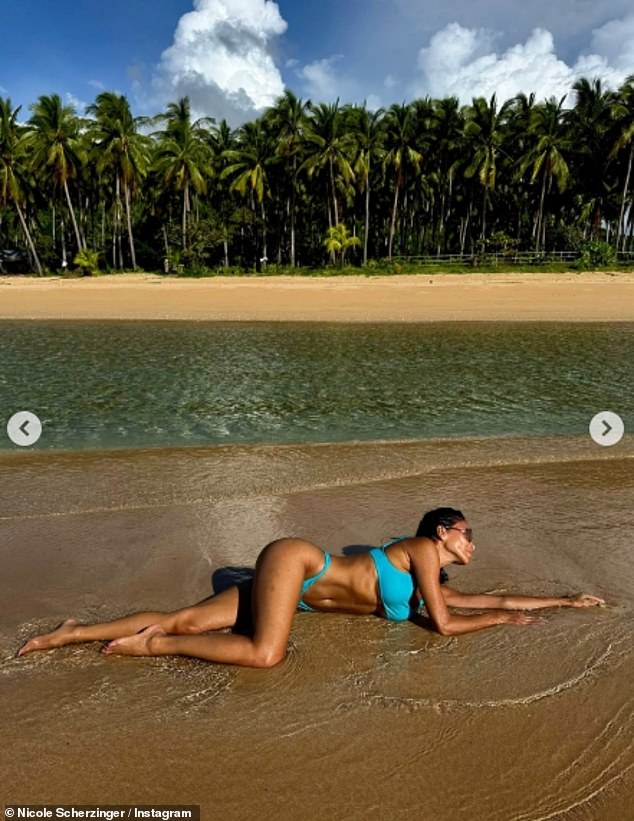 Writhing about in the surf, she twisted to show off her toned stomach and long legs, shielding her face behind oversized sunglasses