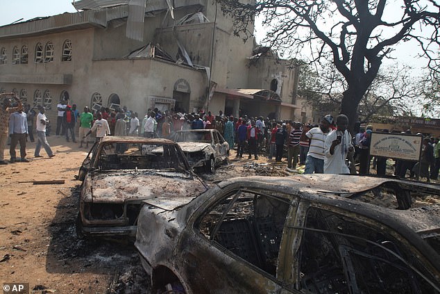 Onlookers gather around burnt our cars at the site of a bomb bast at the St Theresa Catholic Church in 2011. Attacks such as these have been reported for years
