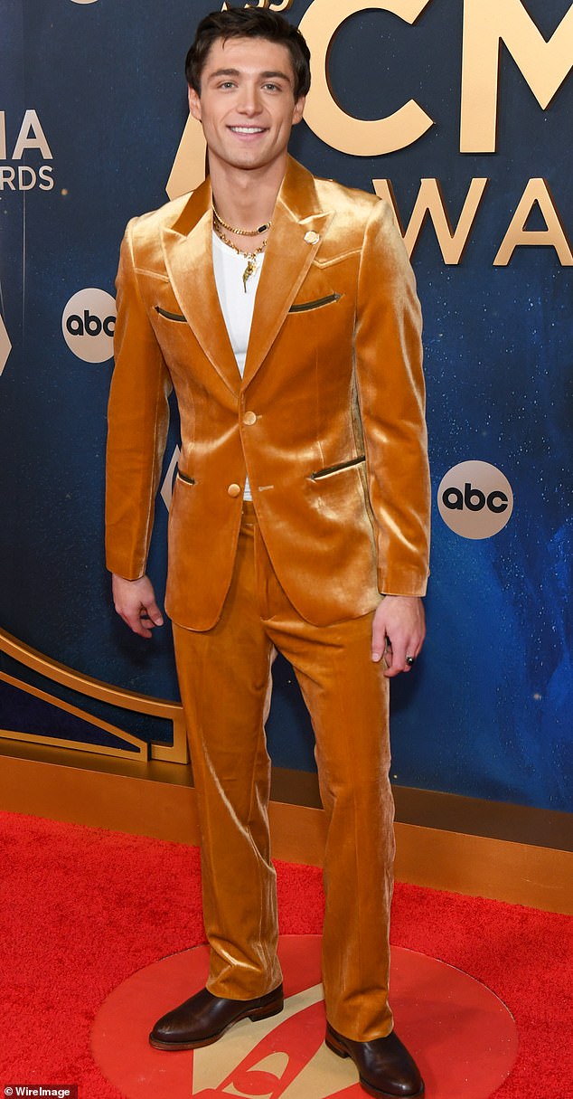 Velvet gone wrong! Actor Asher Angel arrived to the red carpet in a questionable, copper-colored velvet suit. He paired the look with a pair of brown boots and multiple necklaces around his neck