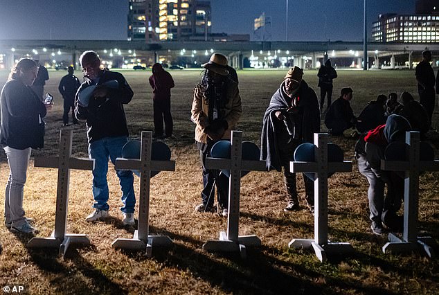 Community members are pictured signing placards placed on crosses at a vigil for those killed in the devastating crash on November 7