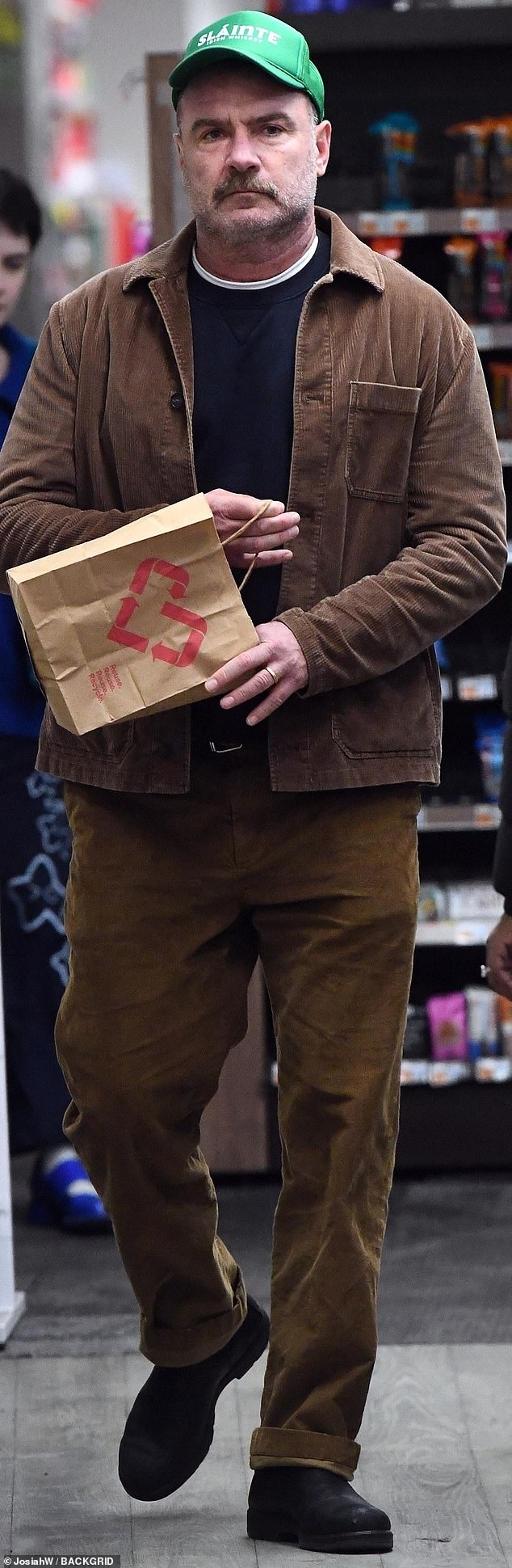 The movie star had on a green Slainte: Irish Whiskey cap with a brown corduroy jacket and matching slacks with his gold wedding band in place as he was alone