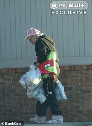 Scott wore baggy black pants, a Von Dutch trucker cap and a black quarter-zip hoodie