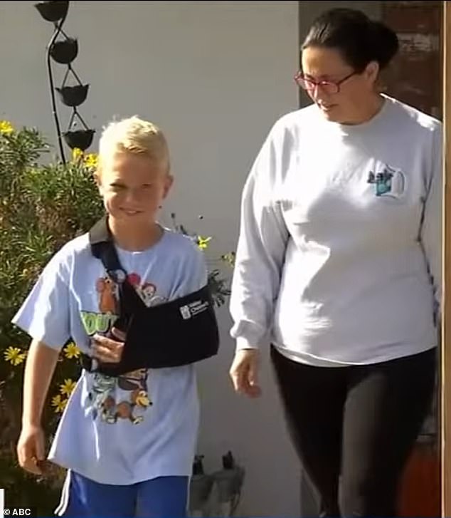 James Harrah, eight, was left with a concussion and bruising when part of his elementary school's ceiling fell on top of him Monday. He is pictured with his mother, Diana