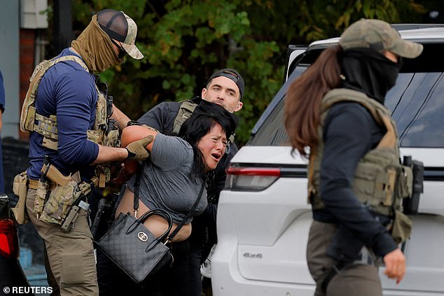 Federal agents, including US Marshalls, FBI agents and HSI agents, detain a woman during an immigration enforcement raid in Massachusetts