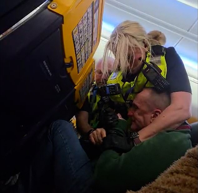 An intoxicated British Ryanair passenger had to be wrestled by police after refusing to sit down for landing - forcing the pilot to circle the airport