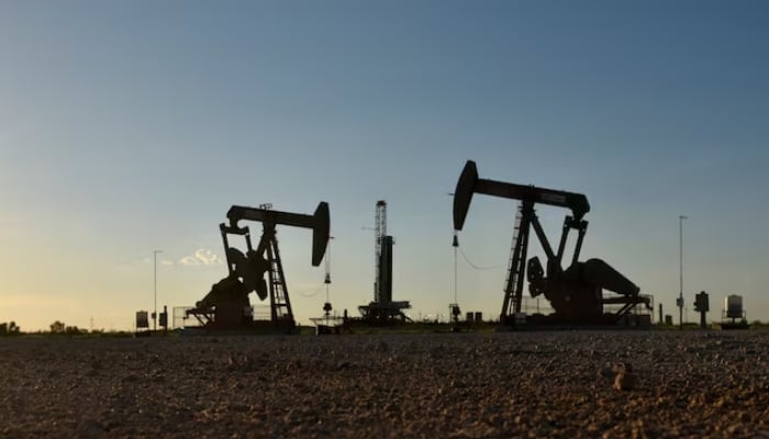 Pump jacks operate in front of a drilling rig in an oil field in Midland, Texas United States. — Reuters/File
