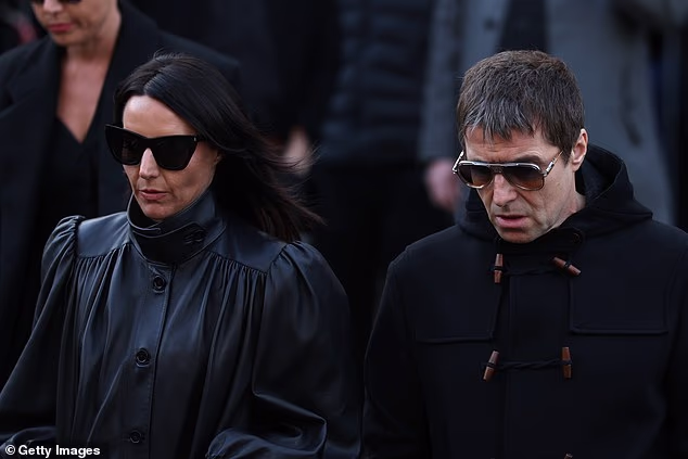 Liam Gallagher and his partner Debbie Gwyther had their head bowed when arriving