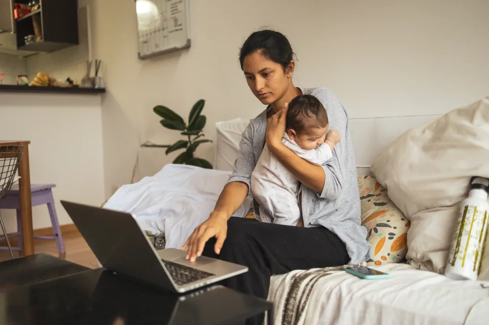 Parent holding child and looking at laptop