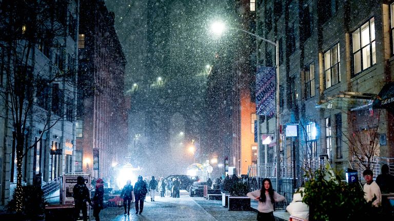 People gather on Washington Street, Brooklyn, as snow falls. Pic: Reuters