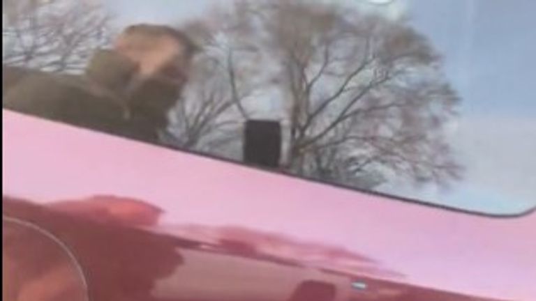 The ICE officer can be seen filming in a reflection.