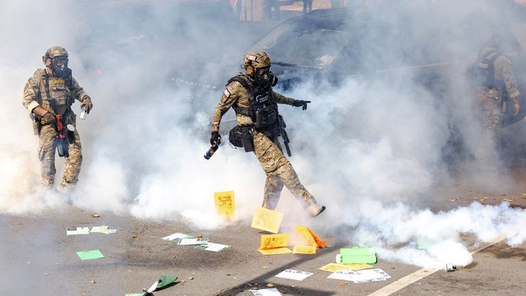 A federal agent kicks a tear gas canister during clashes in Chicago in October. Pic: Reuters