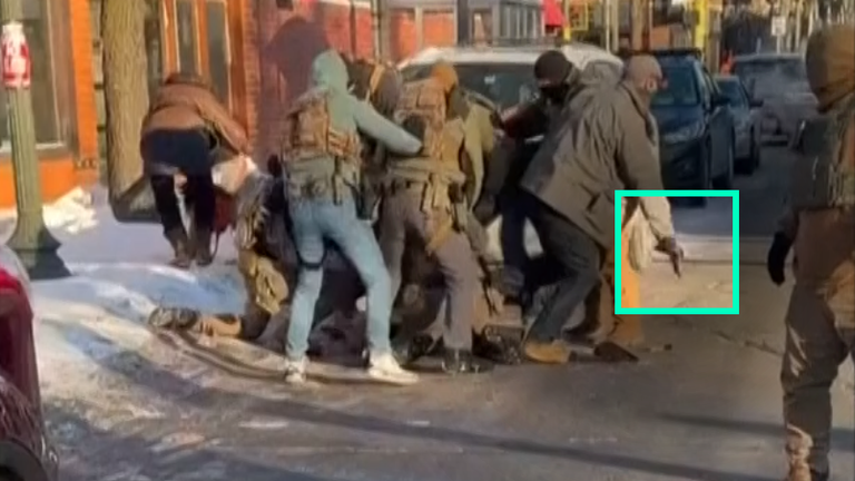 Still shows man in grey jacket leave group with gun