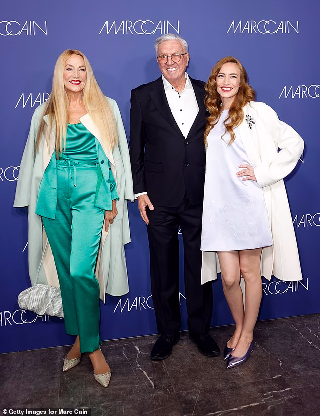 Elizabeth paired the A-line dress with a white longline coat and lilac accessories, including a fringed handbag and metallic stilettos (pictured with Helmut Schlotterer)