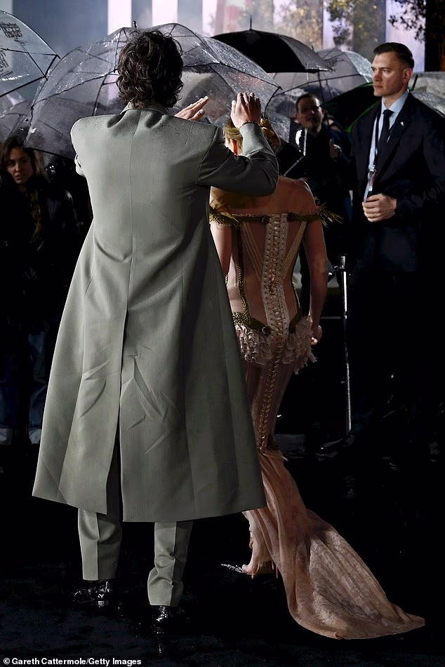 Ever the gentleman, the actor assisted Margot with an umbrella to ensure she stayed dry in the pouring rain as they posed for photos together