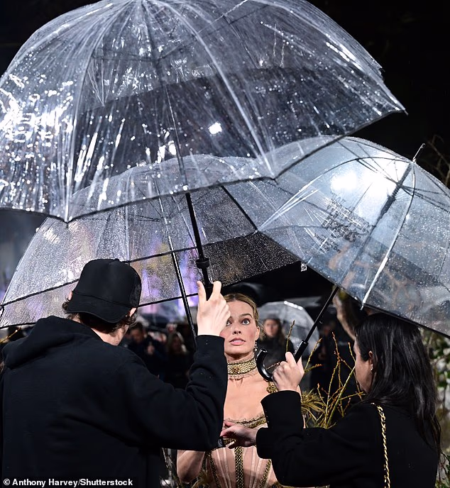 Proving it takes a village, several members of staff were on hand with umbrellas to keep Margot dry in the wet weather