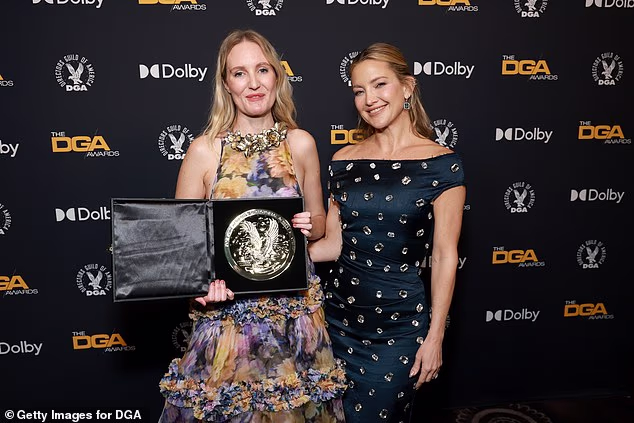 She posed backstage with the shiny medallion alongside Kate Hudson who stunned in a glamorous look