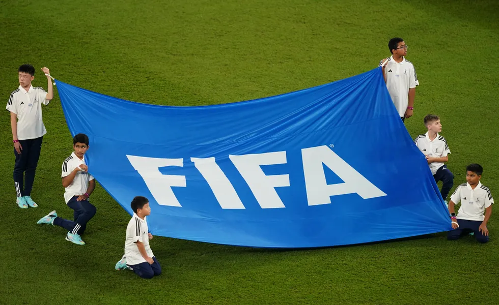 Children hold a banner of the FIFA logo on the pitch before the FIFA World Cup