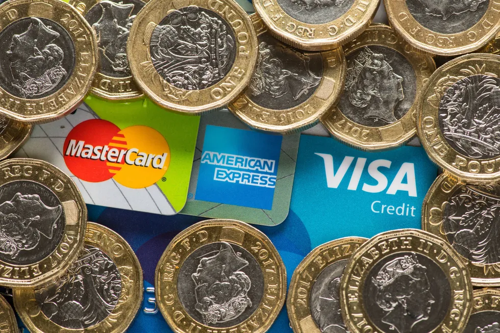 Mastercard, American Express and Visa credit cards with UK one pound coins