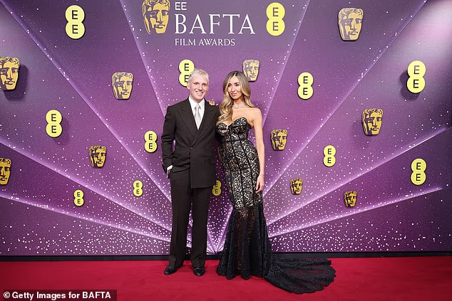 By her side Jamie, 37, looked smart in a black suit and crisp white shirt as he put his arm around his stunning wife