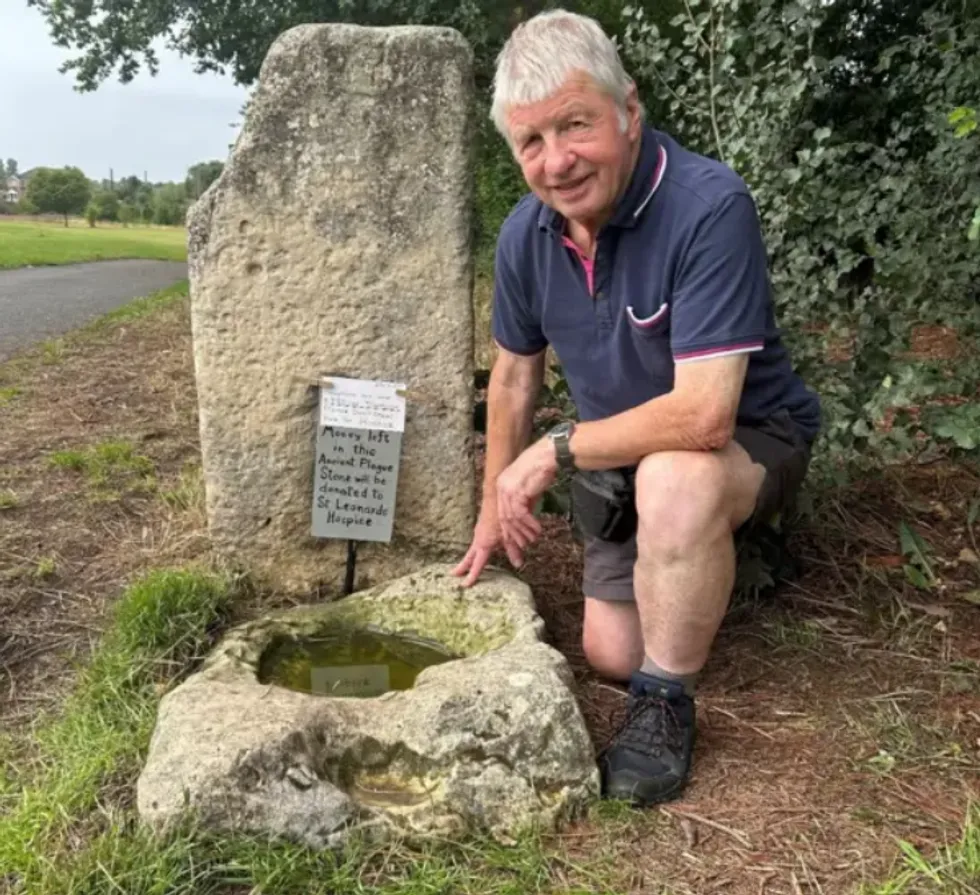 Ian Tomlinson, member of local community conservation group in Yorkshire, kneels next to the Plague Stone located in Hob Moor