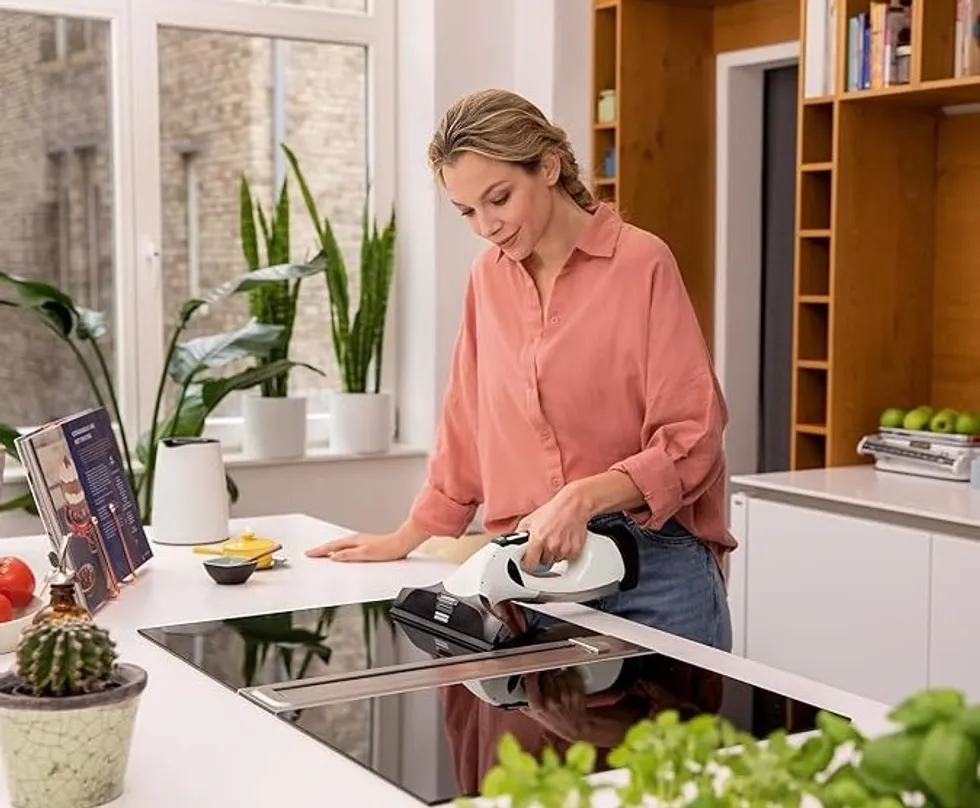 Woman cleaning kitchen stovetop with the K\u00e4rcher Window Vac WV