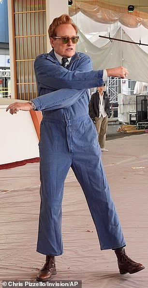 He slipped his towering 6ft 4in frame into a blue-denim jumpsuit over a formal white shirt and blue-dotted necktie along with brown boots