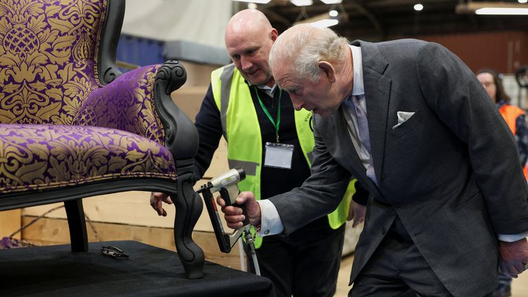 King Charles uses a stapler to help restore a chair during his tour of the Renew Hub in Trafford Park. Pic: PA