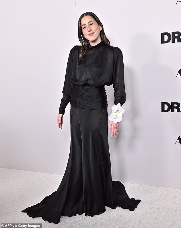 The 34-year-old Haim guitarist - who plays Rachel - opted for a 1930s-style black long-sleeve gown with a gardenia corsage on her wrist selected by styling sisters Chloe and Chenelle Delgadillo