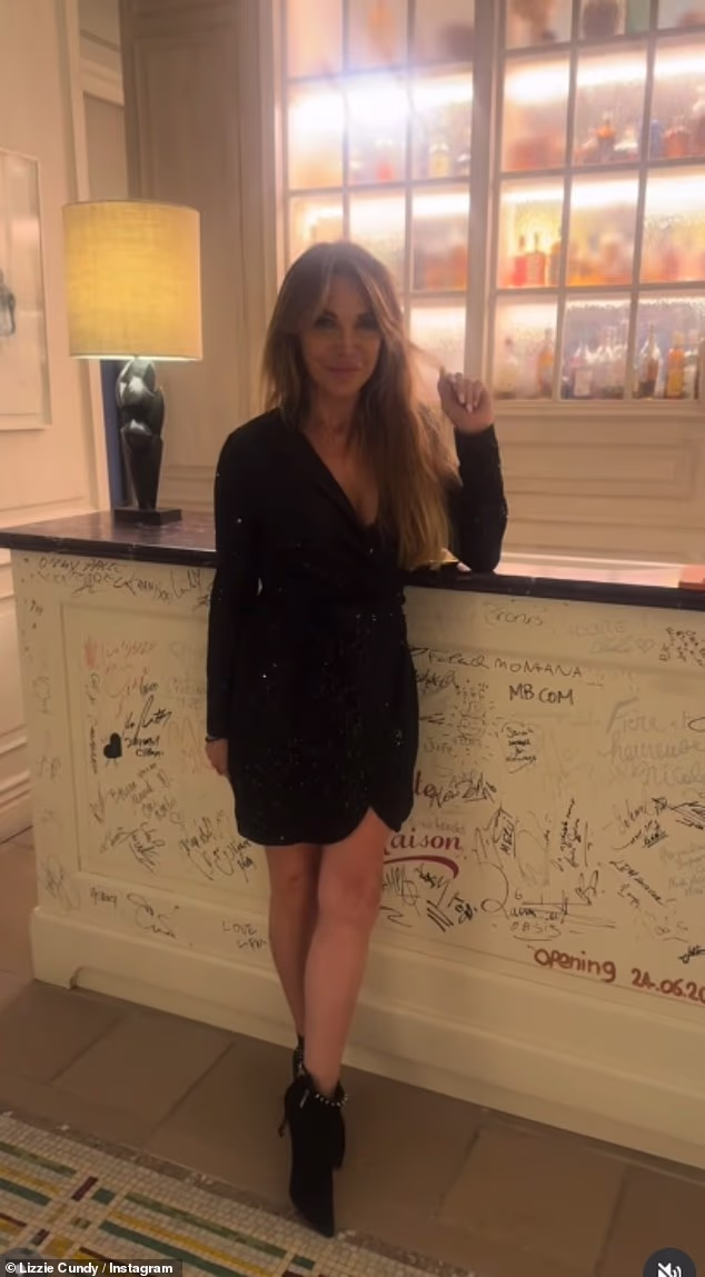 Lizzie cut a glamorous figure in a black minidress and boots as she posed for a photo at the restaurant