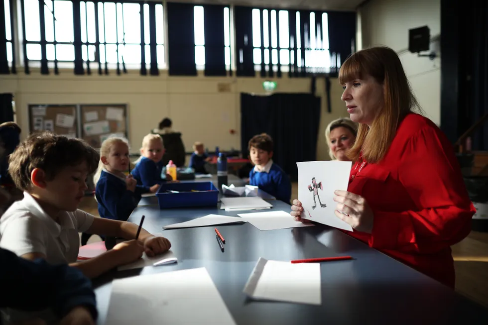 Angela Rayner holds up a drawing of what looks like a monster to some school children
